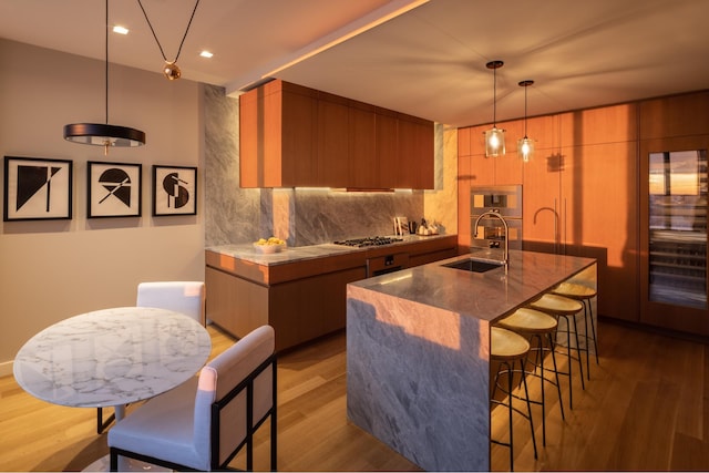 kitchen featuring a sink, a breakfast bar area, light wood-style flooring, modern cabinets, and recessed lighting