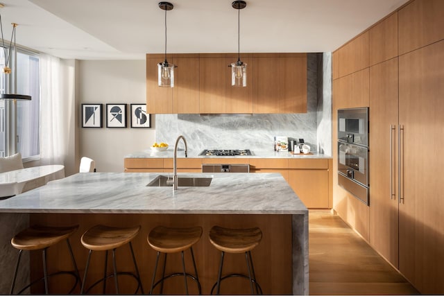 kitchen featuring a sink, appliances with stainless steel finishes, modern cabinets, decorative backsplash, and light wood-style flooring