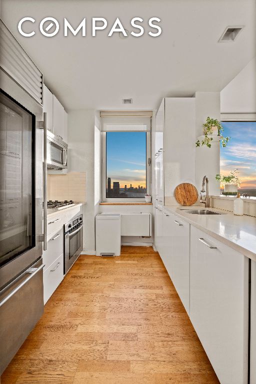 kitchen featuring a sink, visible vents, white cabinetry, light countertops, and appliances with stainless steel finishes