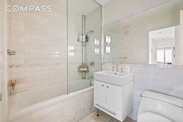 bathroom with toilet, vanity, tile walls, and tiled shower / bath