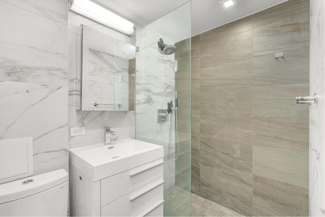 bathroom featuring tile walls, toilet, vanity, and a tile shower