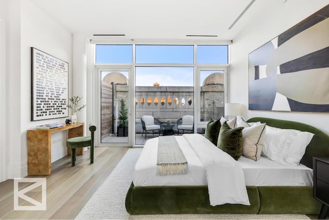 bedroom with floor to ceiling windows, multiple windows, and light wood-type flooring