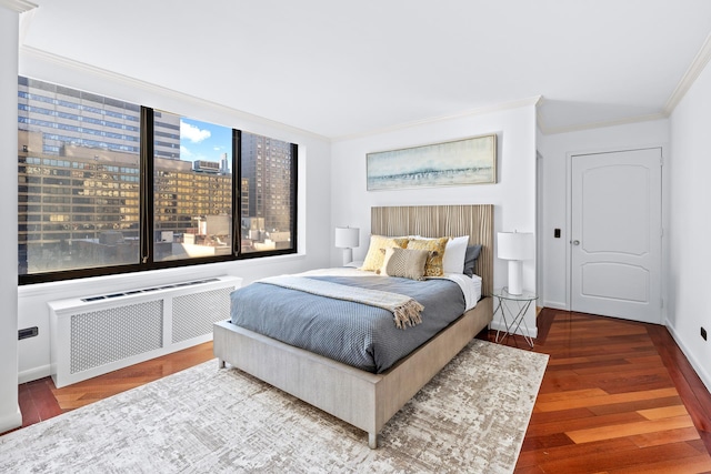 bedroom with a city view, crown molding, radiator heating unit, wood finished floors, and baseboards