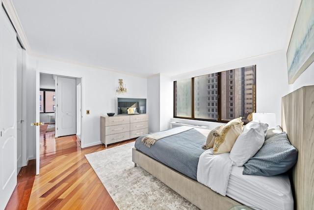 bedroom with baseboards, crown molding, and wood finished floors