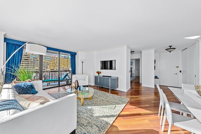 living area with crown molding, baseboards, wood finished floors, and floor to ceiling windows