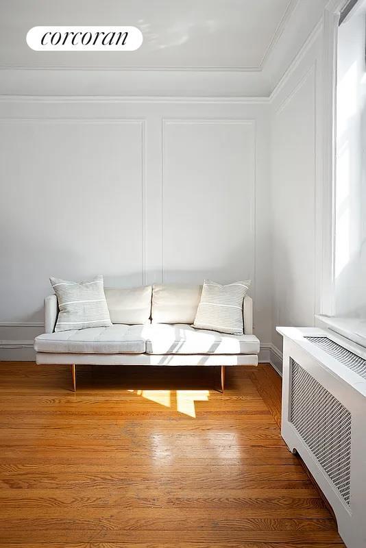 sitting room with baseboards, ornamental molding, and wood finished floors
