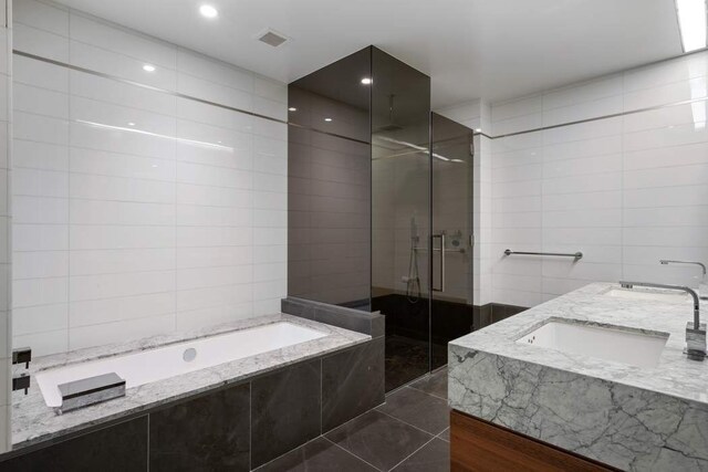 bathroom with tile patterned floors, vanity, tile walls, and plus walk in shower