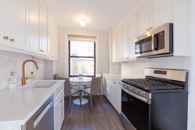 kitchen with appliances with stainless steel finishes, white cabinetry, and a sink