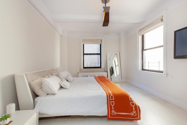 bedroom with radiator heating unit, beam ceiling, and baseboards