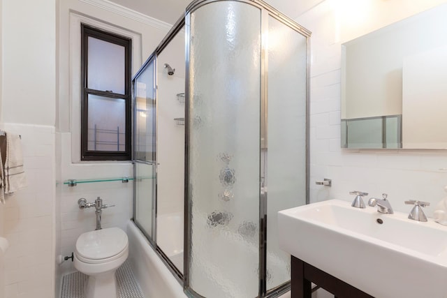 full bathroom featuring tile walls, toilet, enclosed tub / shower combo, and a sink