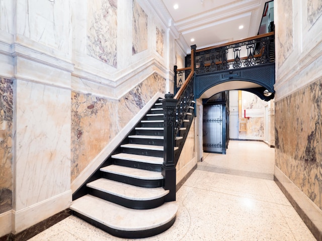 staircase with a high ceiling and ornamental molding