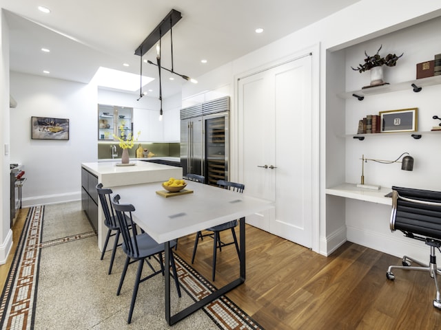 interior space with white cabinetry, hanging light fixtures, dark hardwood / wood-style flooring, built in refrigerator, and built in desk