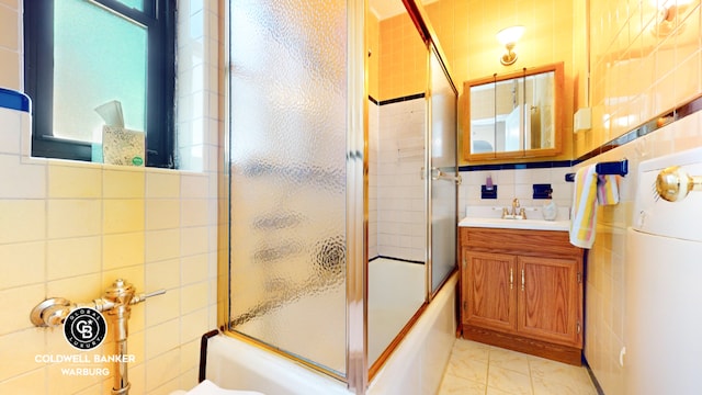 bathroom with toilet, shower / bath combination with glass door, vanity, and tile walls