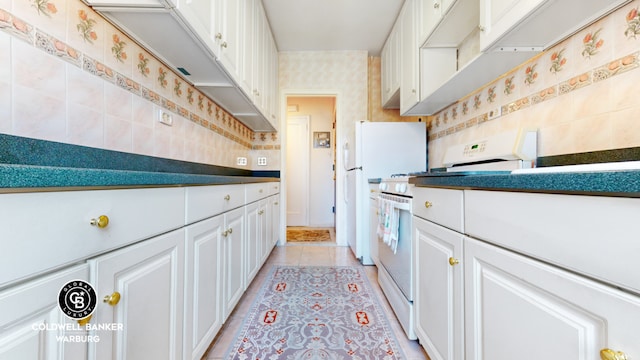 kitchen featuring light tile patterned floors, white gas range, backsplash, white cabinets, and wallpapered walls