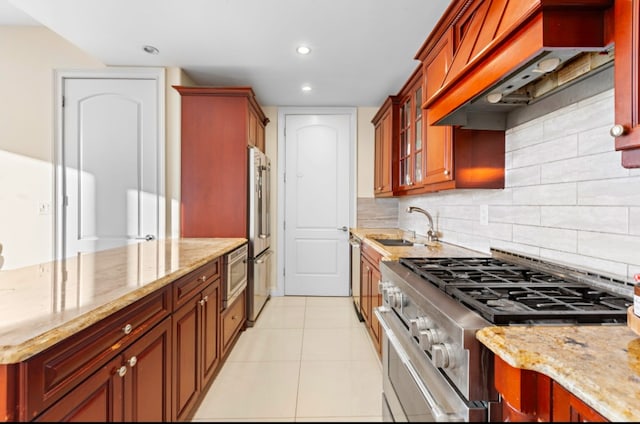 kitchen with stainless steel appliances, tasteful backsplash, premium range hood, sink, and light stone counters