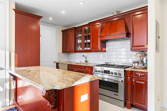 kitchen featuring custom range hood, a sink, backsplash, stainless steel appliances, and dark brown cabinets