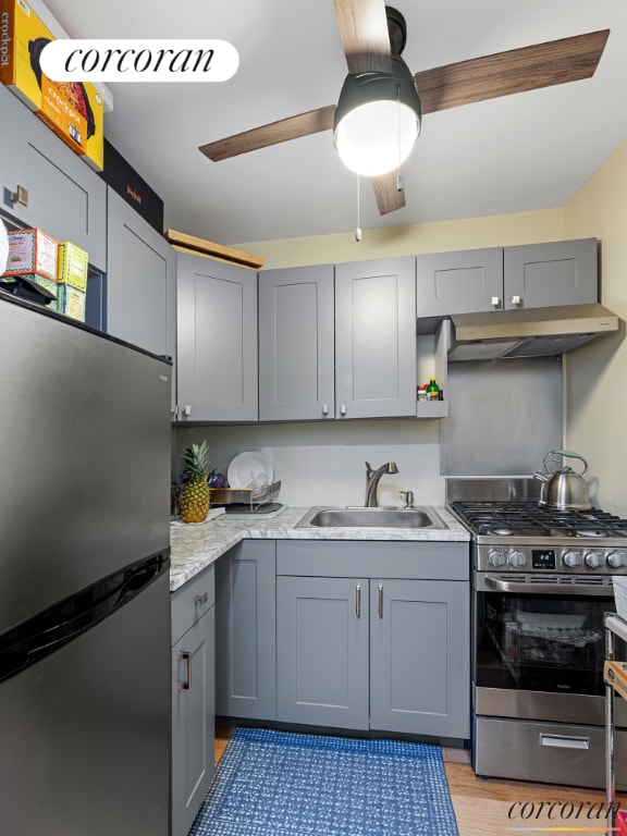 kitchen with extractor fan, sink, light wood-type flooring, ceiling fan, and stainless steel appliances