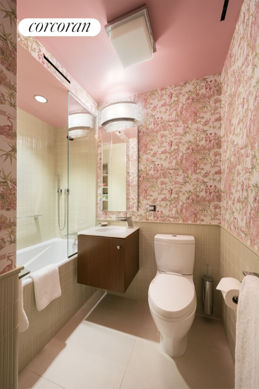 full bathroom with tiled shower / bath combo, tile patterned flooring, vanity, and toilet