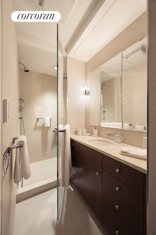 bathroom featuring a tile shower, tile patterned flooring, and vanity