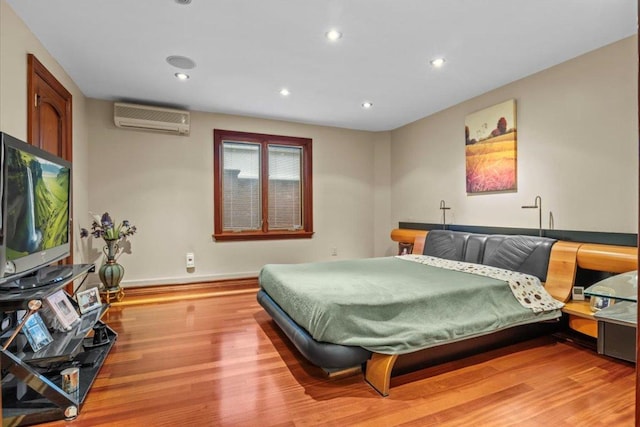 bedroom with hardwood / wood-style flooring and a wall unit AC