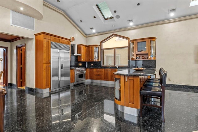 kitchen featuring wall chimney range hood, a breakfast bar, high vaulted ceiling, high end appliances, and kitchen peninsula