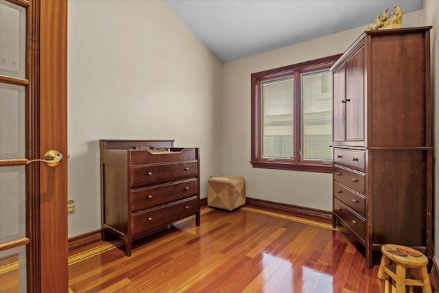 bedroom with wood-type flooring and vaulted ceiling