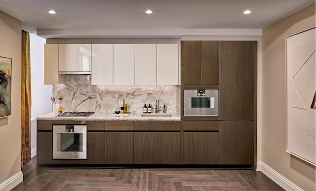 kitchen with appliances with stainless steel finishes, dark parquet floors, white cabinetry, sink, and backsplash