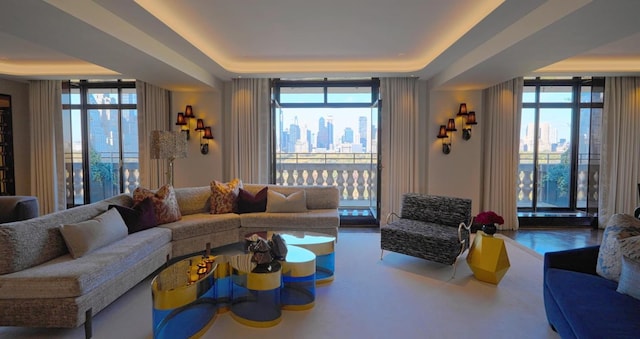 living room with a wall of windows, a raised ceiling, and plenty of natural light