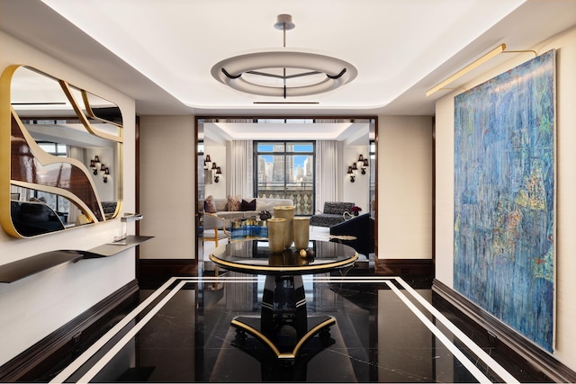 dining room featuring a tray ceiling, breakfast area, and baseboards