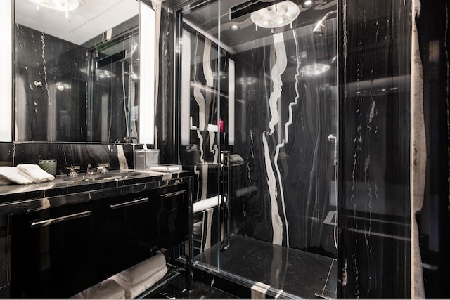 full bathroom with a marble finish shower and vanity