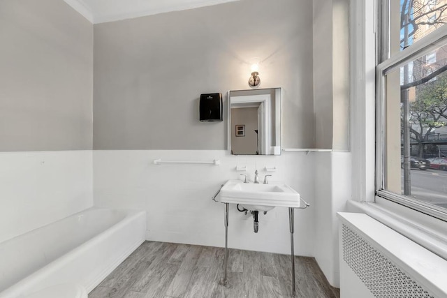 bathroom featuring hardwood / wood-style flooring, a tub to relax in, and radiator heating unit