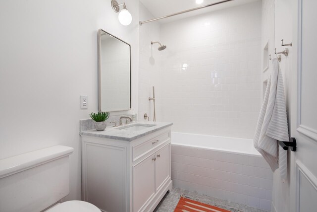 bathroom featuring toilet, vanity, tiled shower / bath combo, and tile patterned floors