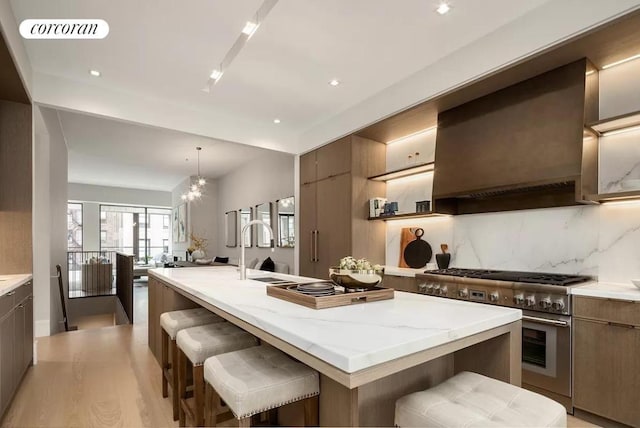 kitchen featuring high end stainless steel range, a kitchen breakfast bar, and a center island with sink