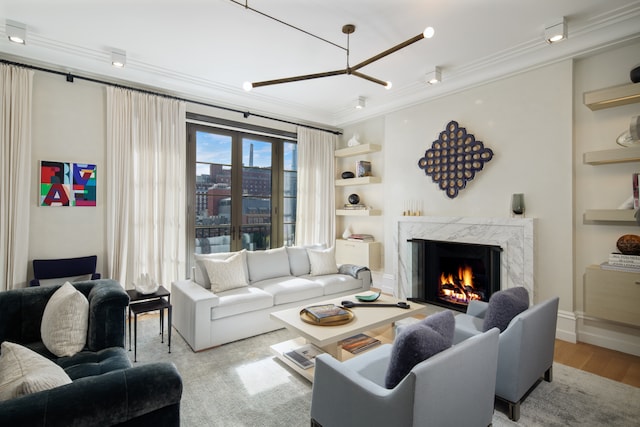 living room with a high end fireplace, wood finished floors, and ornamental molding