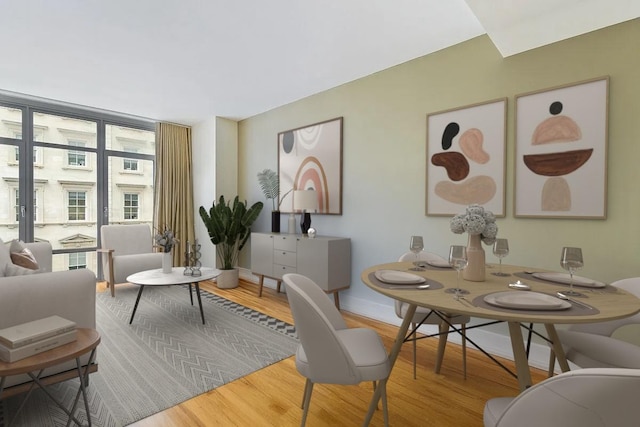 dining space with a wall of windows, baseboards, and wood finished floors