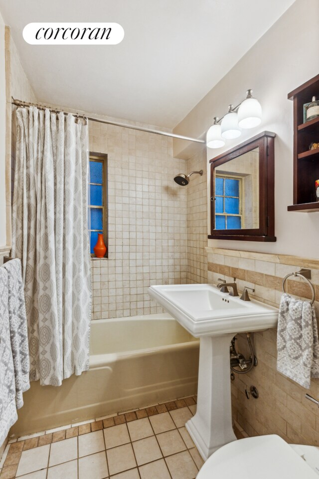 bathroom with tile patterned flooring, toilet, tile walls, and shower / bath combo with shower curtain