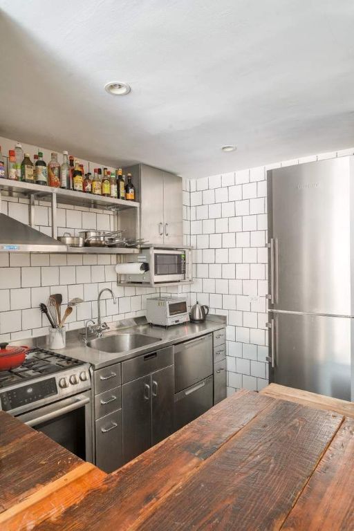 kitchen featuring sink, stainless steel appliances, wood counters, and backsplash