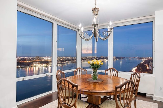 dining area featuring a water view, hardwood / wood-style floors, and an inviting chandelier