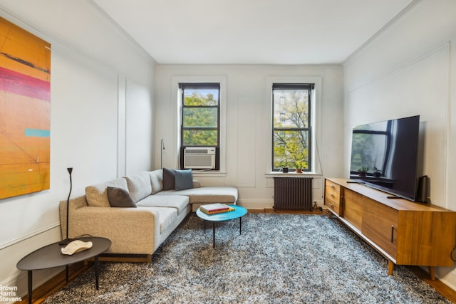 living room with cooling unit, radiator, baseboards, and wood finished floors