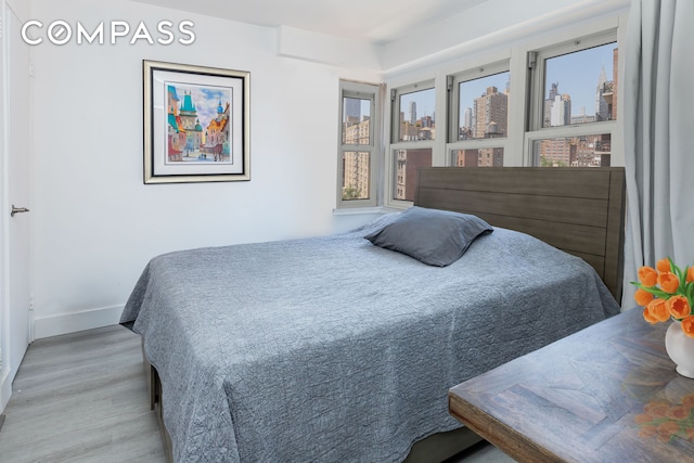 bedroom featuring a city view, baseboards, and wood finished floors