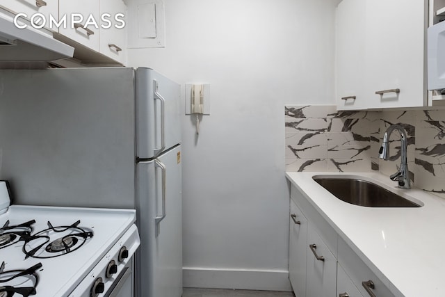 kitchen featuring light countertops, white appliances, a sink, and decorative backsplash