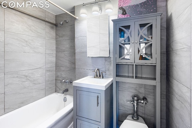 bathroom with shower / bathing tub combination, vanity, and tile walls