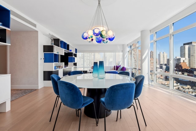 dining space with an inviting chandelier, a city view, wood finished floors, and a wall of windows