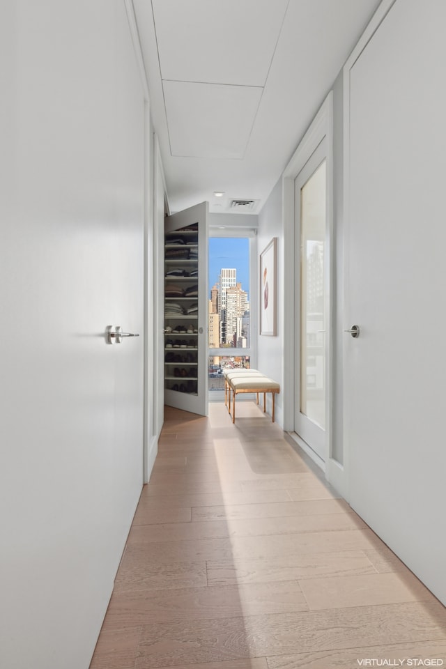 corridor with a city view, visible vents, and light wood-style flooring