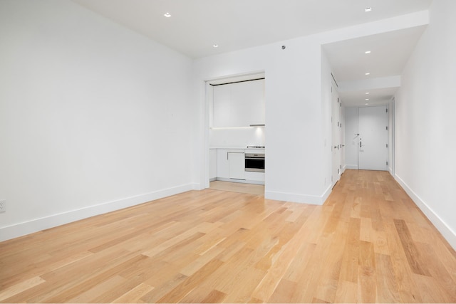 unfurnished living room with light wood-type flooring and baseboards