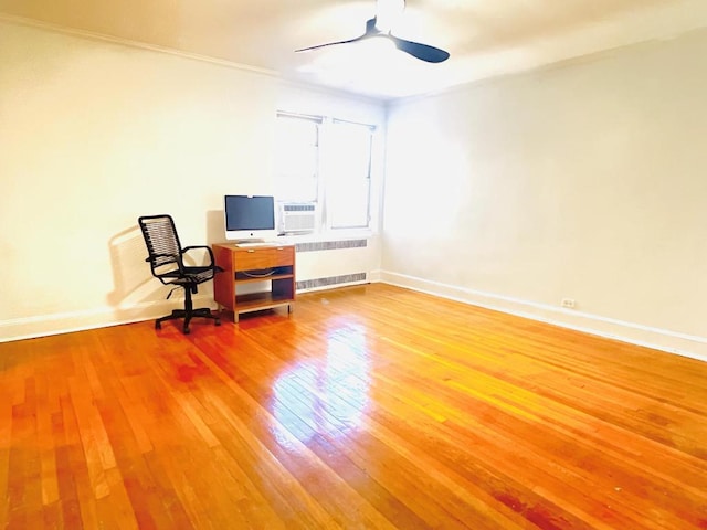 unfurnished office featuring hardwood / wood-style flooring, radiator heating unit, and ceiling fan