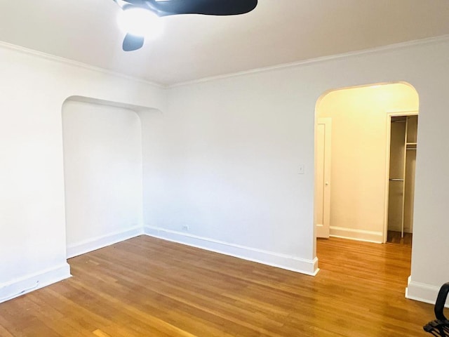 empty room featuring crown molding, ceiling fan, and wood-type flooring