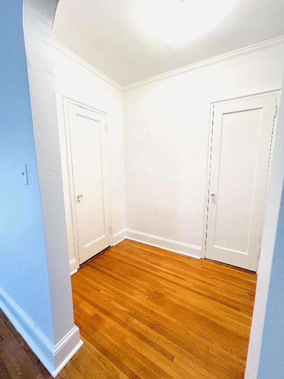 unfurnished room featuring wood-type flooring and crown molding