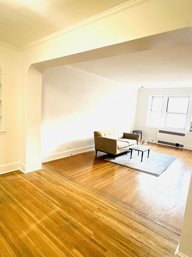 unfurnished room featuring baseboards, ornamental molding, wood finished floors, and radiator