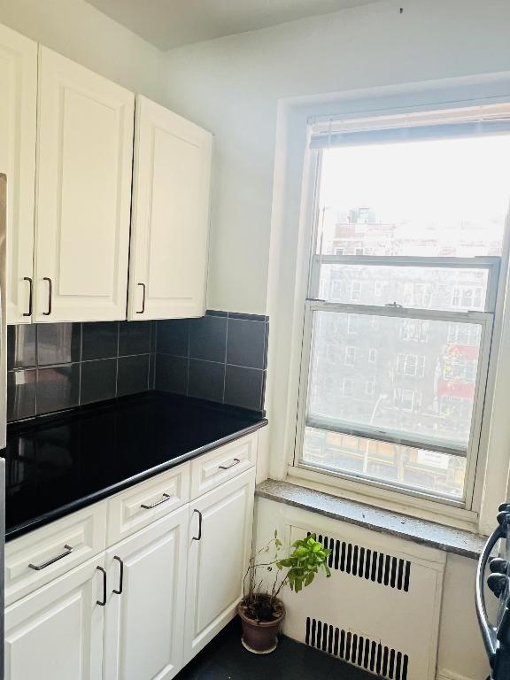 kitchen with white cabinetry, radiator heating unit, and decorative backsplash